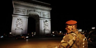a soldier stand near the arc de triomphe