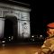 a soldier stand near the arc de triomphe